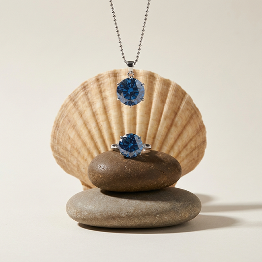 Astrielle 10-carat blue moissanite ring and pendant necklace set in sterling silver by MerchLuxx on stones with a shell in the background