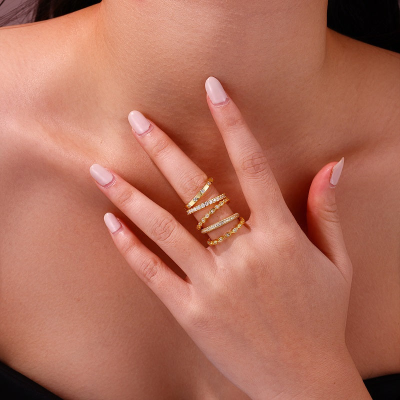 Close-up of a hand wearing the Aurielle moissanite stackable ring set in 18K gold-plated sterling silver, layered with luxury bands by MerchLuxx on a neutral background