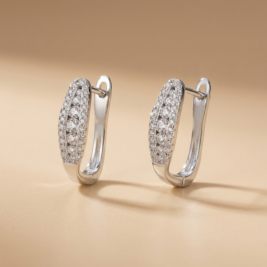 Pair of Pavé moissanite hoop earrings in rhodium-plated sterling silver by MerchLuxx on a beige background