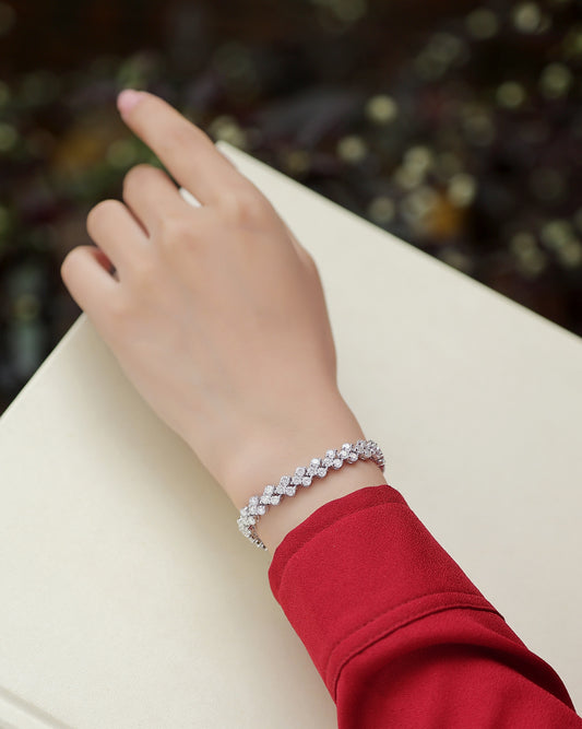 A hand wearing a Luminara moissanite cluster tennis bracelet in S925 sterling silver luxury wrist jewelry by MerchLuxx on a blurred background
