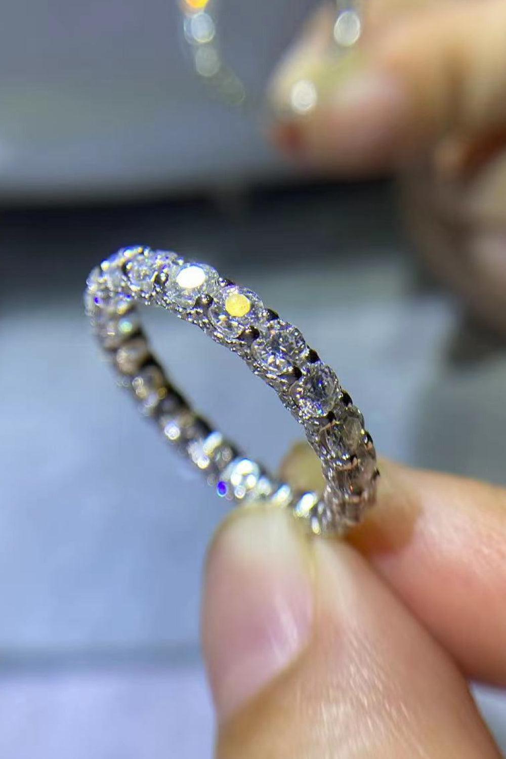 Close-up of the Eternyx™ Moissanite Eternity Ring held between fingers