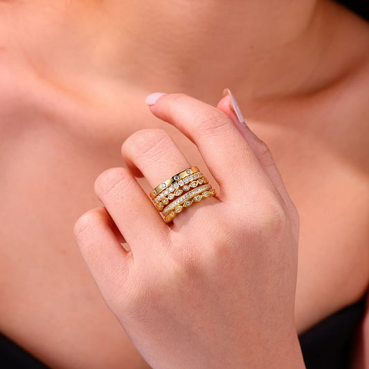 Hand wearing the Aurielle moissanite stackable ring set in 18K gold-plated sterling silver, layered luxury bands by MerchLuxx with a blurred background