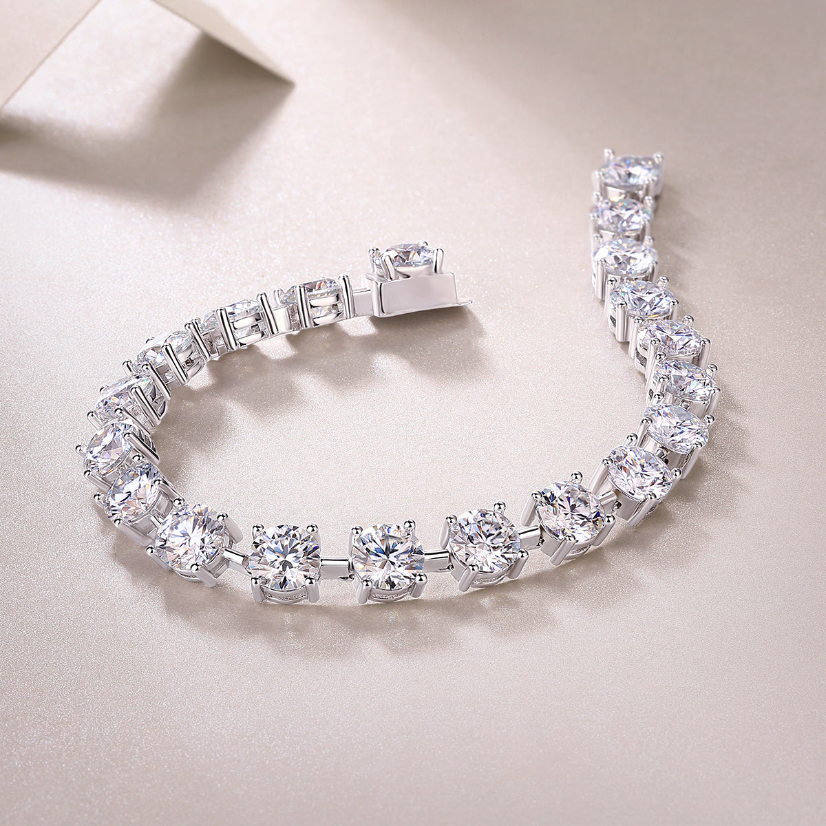 Tempéra moissanite tennis bracelet in S925 sterling silver with round brilliant stones, luxury jewelry by MerchLuxx on a light beige background