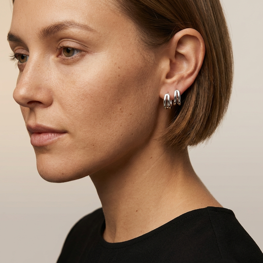Close-up of a woman wearing925 sterling silver zircon huggie earrings with subtle sparkle on a neutral background
