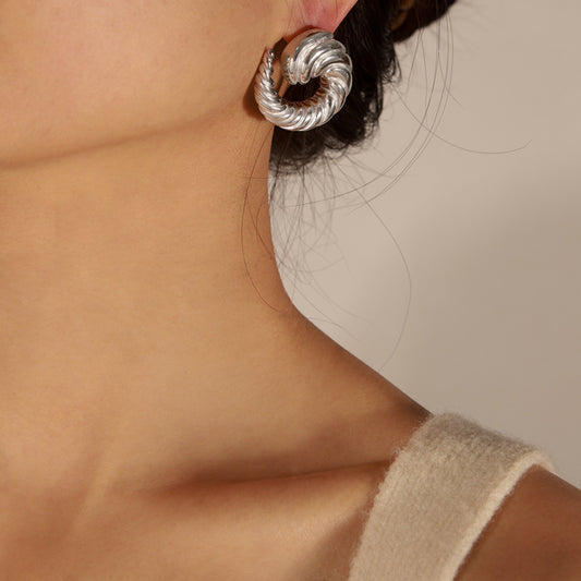 Close-up shot of a woman wearing Silver-tone spiral stud earrings with twisted rope texture