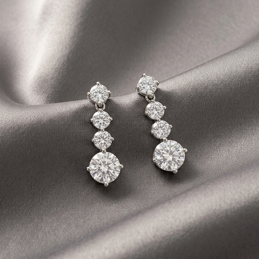 Celestia™ Moissanite Drop Earrings  on a draped gray satin fabric.