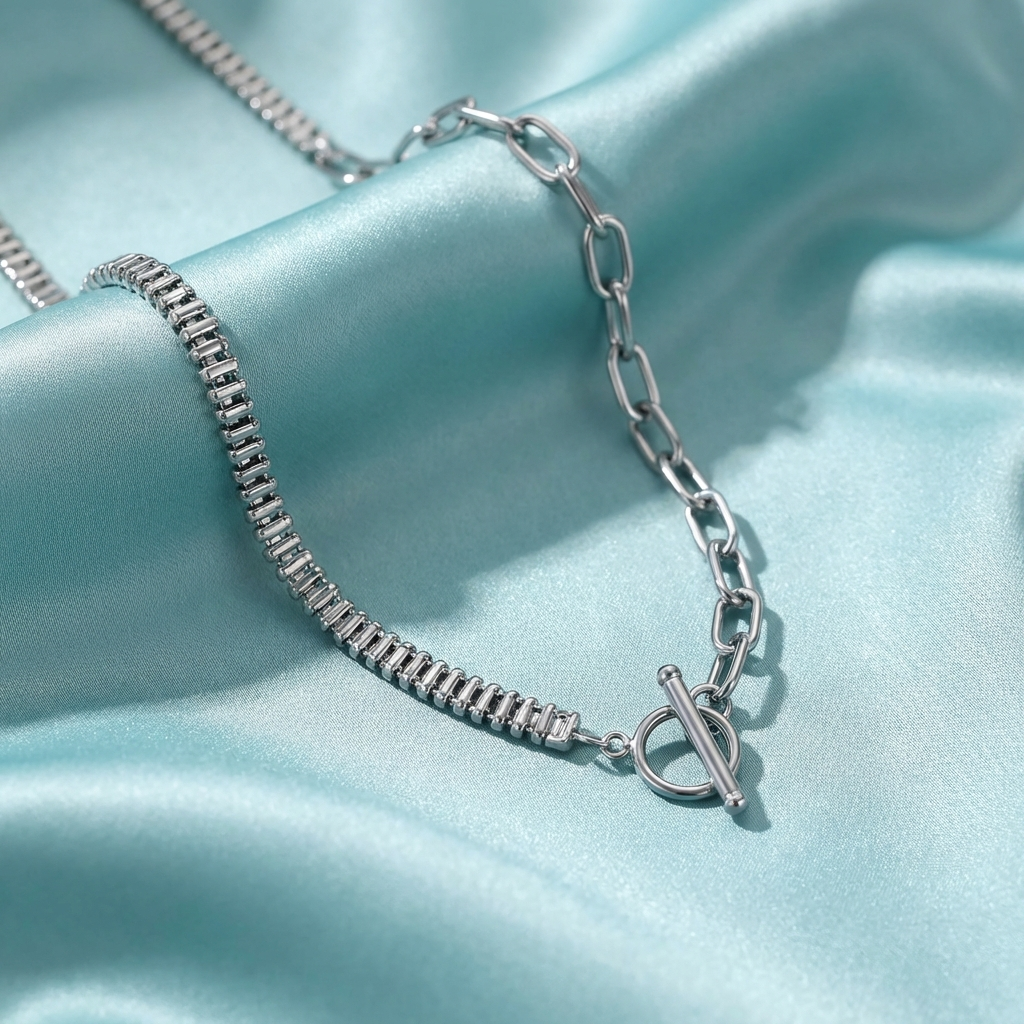 Asymmetric toggle necklace with zircon bar and polished steel chain design  on a light blue satin background