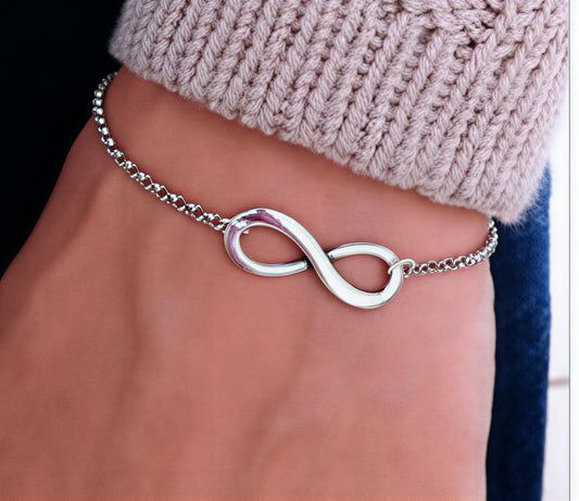 Infinité polished silver infinity symbol bracelet, minimalist, adjustable, luxury bracelet by MerchLuxx with a blurred background