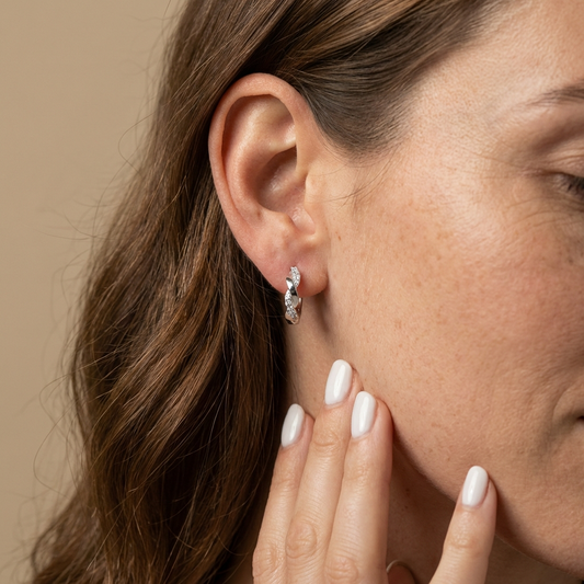 Close up of a woman wearing the Platinum-plated sterling silver twisted channel set moissanite hoop earrings by MerchLuxx