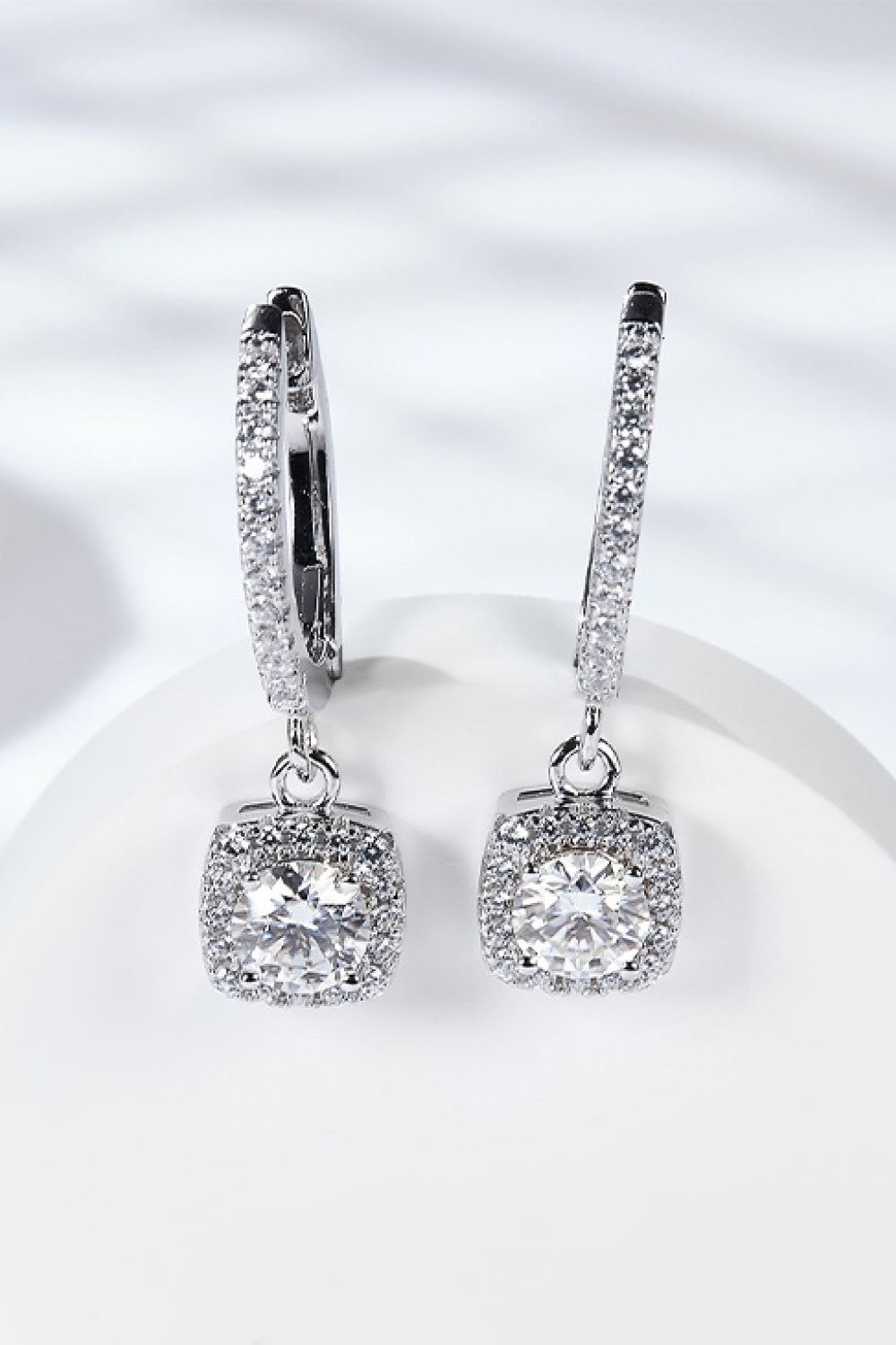 Moissanite huggie drop earrings in sterling silver on a white background