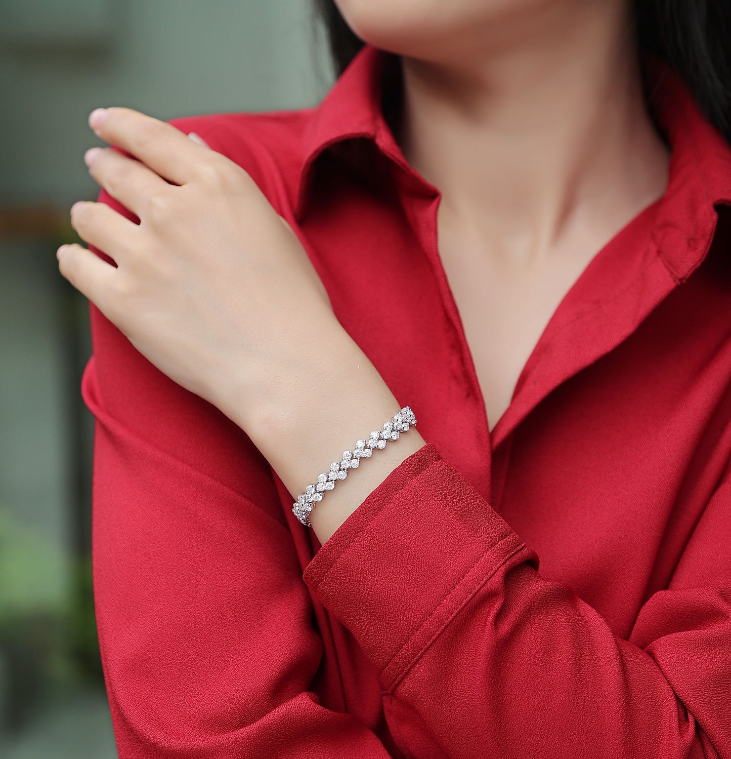 Person wearing a Luminara moissanite cluster tennis bracelet in S925 sterling silver luxury wrist jewelry by MerchLuxx  a blurred background