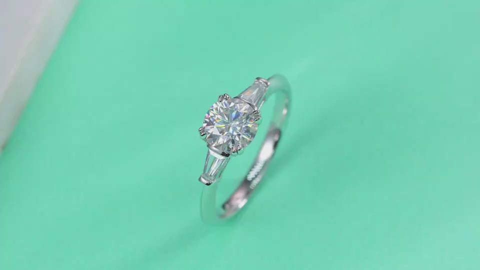 A video showing the sparkle of the Virella 1 carat moissanite three-stone ring in S925 sterling silver with baguette side stones, luxury engagement ring by MerchLuxx 