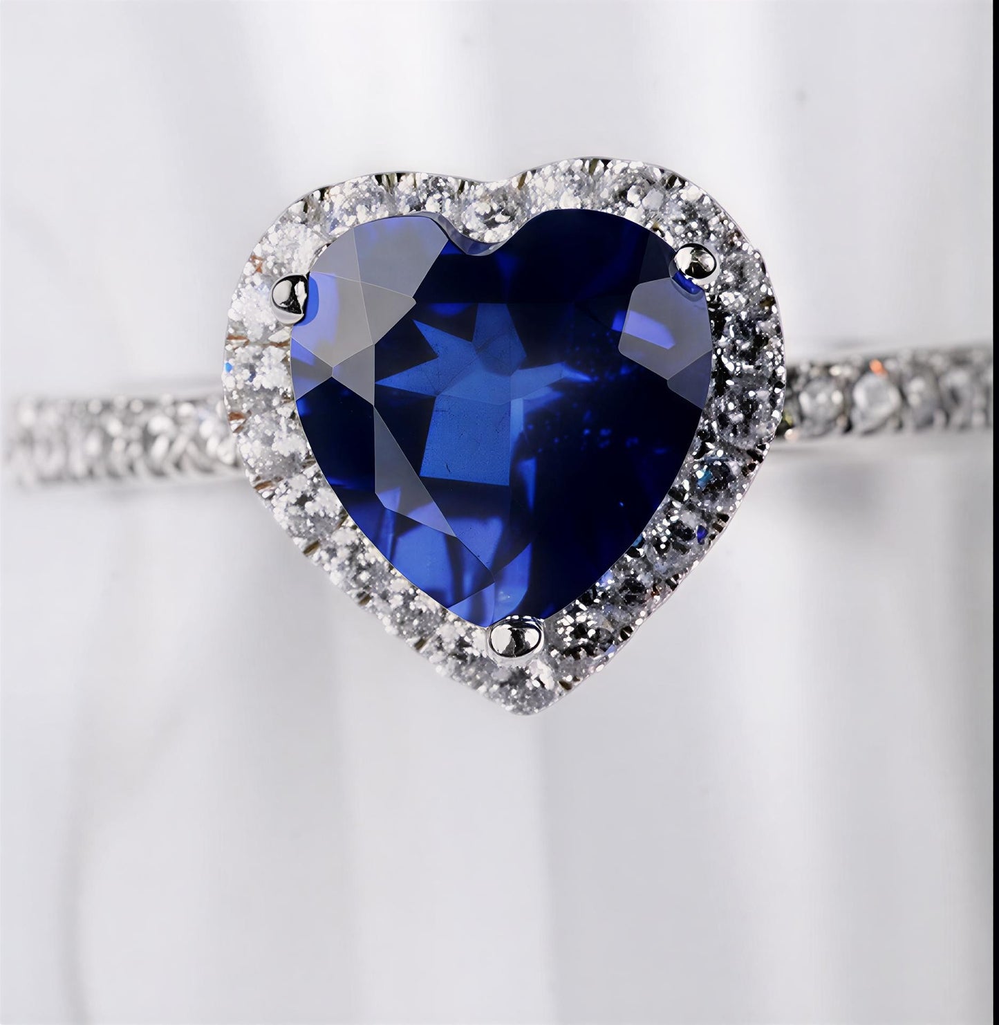 2 carat blue heart moissanite ring in platinum-plated sterling silver with pavé side stones on a white background
