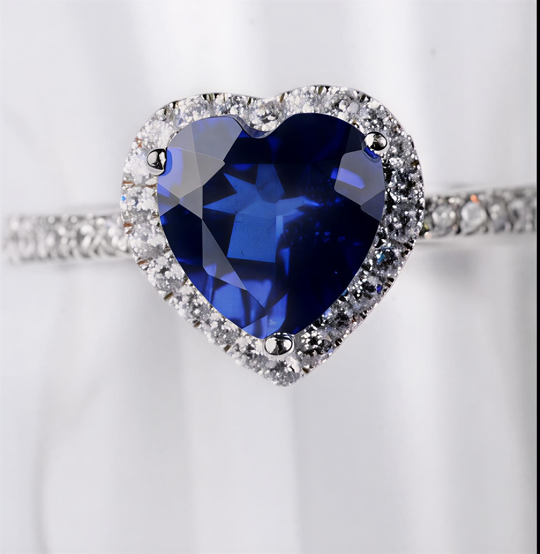 2 carat blue heart moissanite ring in platinum-plated sterling silver with pavé side stones on a white background